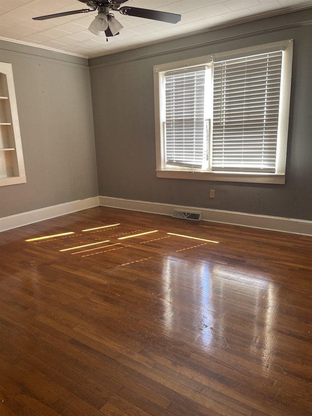 unfurnished room featuring a ceiling fan, visible vents, baseboards, and wood finished floors