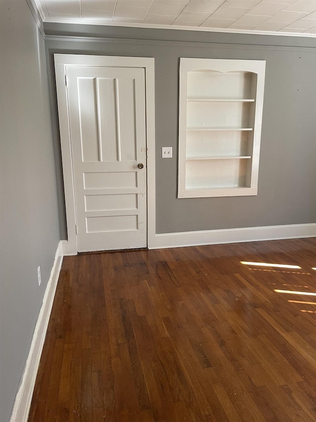 entryway with ornamental molding, dark wood finished floors, and baseboards