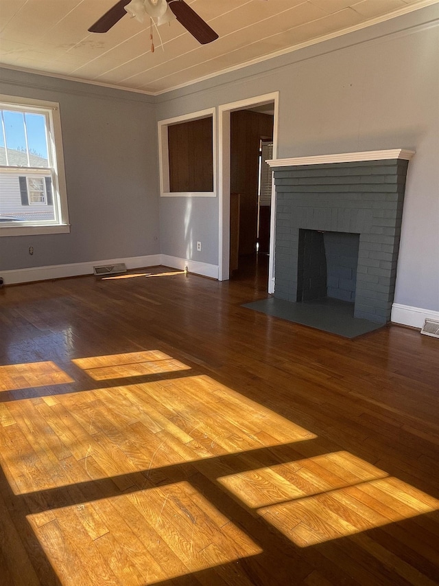 unfurnished living room featuring wood finished floors, visible vents, baseboards, ornamental molding, and a brick fireplace