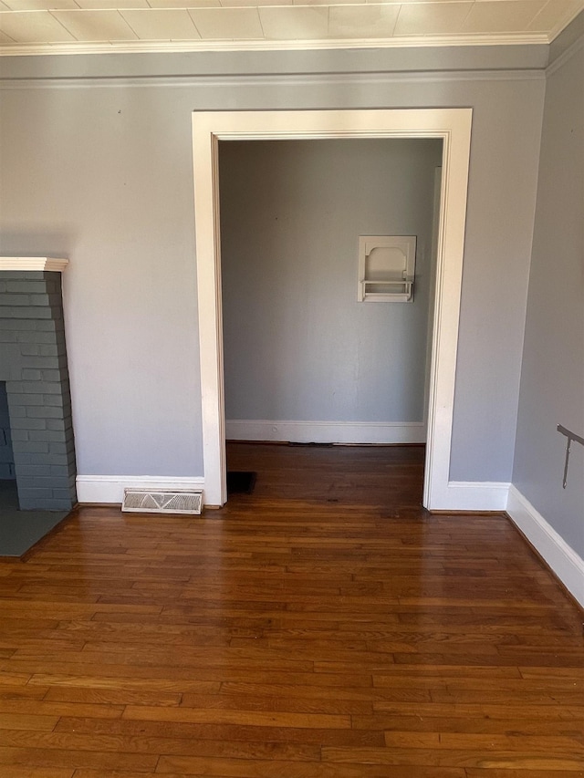 empty room with baseboards, visible vents, wood finished floors, and ornamental molding