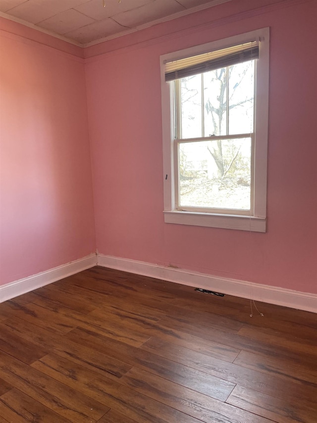 spare room featuring baseboards, dark wood-type flooring, and crown molding