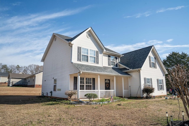 traditional-style home featuring a porch, roof with shingles, and a front yard