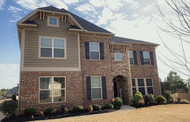 view of front of house featuring roof with shingles and brick siding