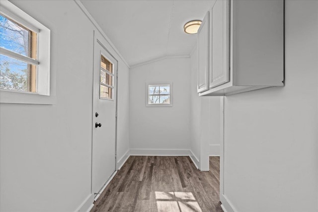 doorway with baseboards, vaulted ceiling, and wood finished floors