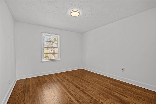 unfurnished room with dark wood-style flooring, baseboards, and a textured ceiling