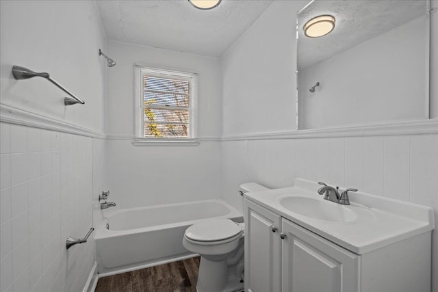 bathroom with a wainscoted wall, wood finished floors, toilet, and a textured ceiling