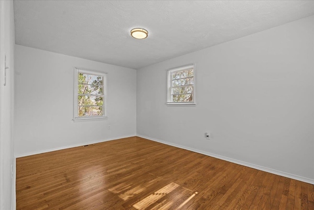 spare room featuring baseboards, a textured ceiling, and wood finished floors