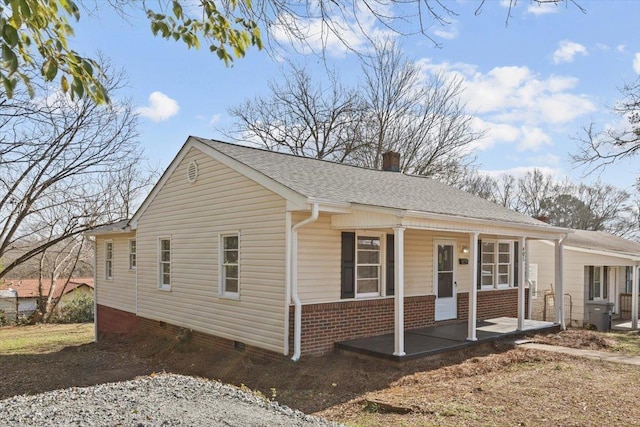 view of front facade with crawl space, a chimney, a shingled roof, and a porch