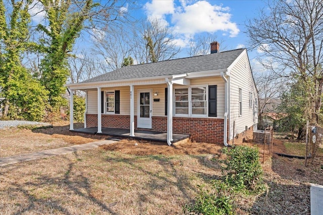 view of front facade featuring brick siding, a porch, and a chimney