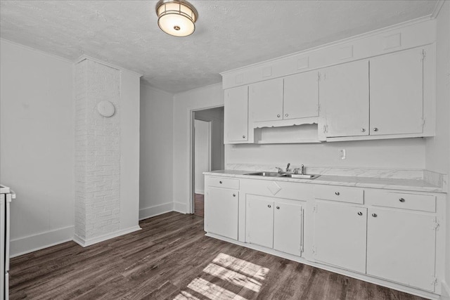 kitchen featuring dark wood-style flooring, light countertops, a sink, and white cabinets