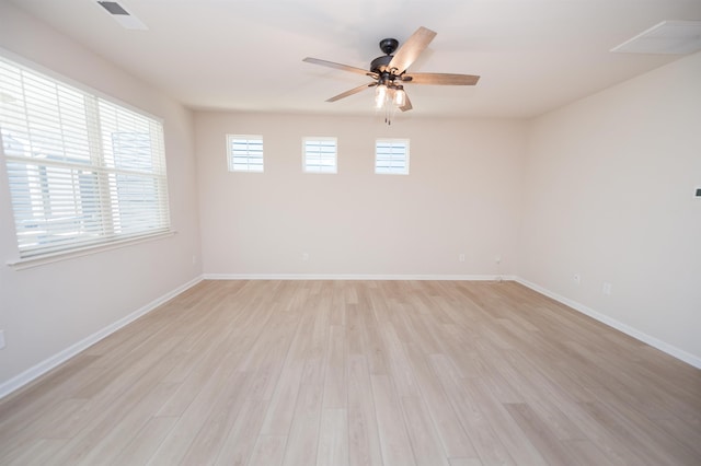 empty room featuring light wood finished floors, visible vents, baseboards, and a ceiling fan