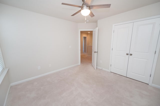 unfurnished bedroom featuring ceiling fan, baseboards, a closet, and light colored carpet