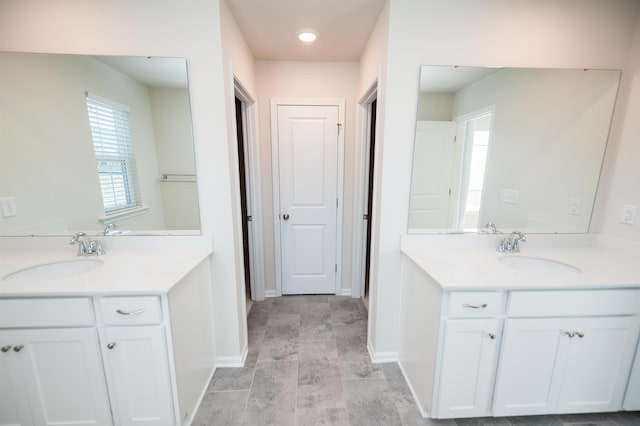 full bath featuring two vanities, a sink, and baseboards