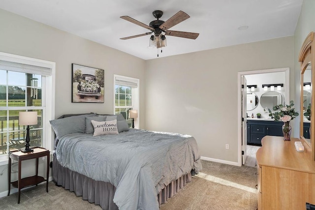 bedroom with connected bathroom, baseboards, a ceiling fan, and light colored carpet