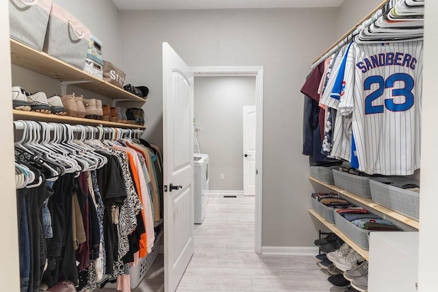 walk in closet featuring wood finished floors and washer and dryer