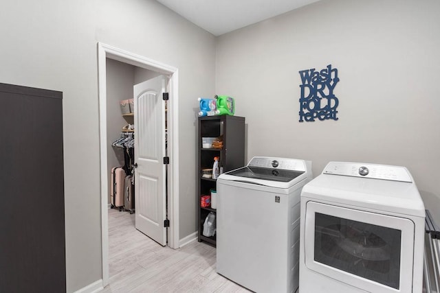 laundry area featuring laundry area, washing machine and dryer, baseboards, and light wood finished floors