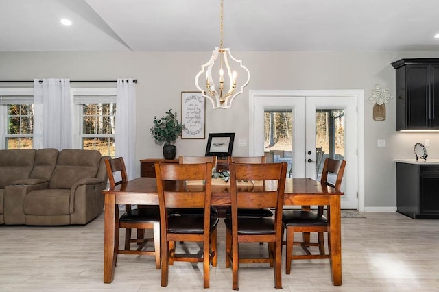 dining room featuring light wood-type flooring, french doors, a notable chandelier, and plenty of natural light