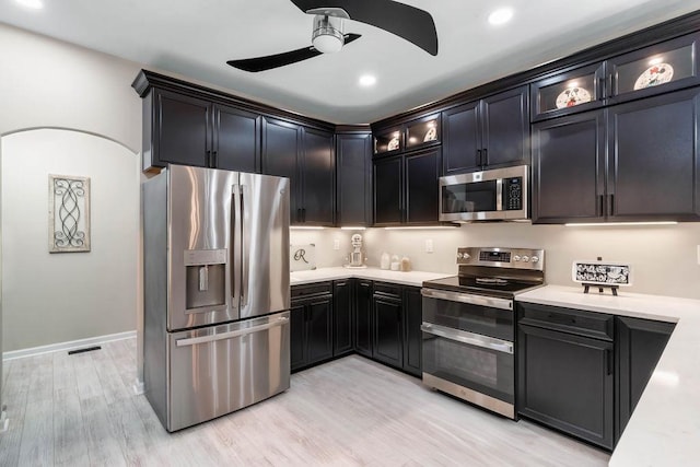 kitchen with stainless steel appliances, light countertops, visible vents, light wood-style flooring, and glass insert cabinets