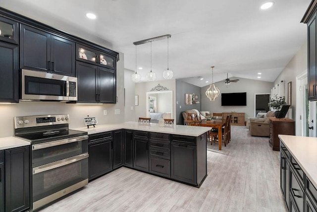 kitchen with lofted ceiling, stainless steel appliances, light countertops, and glass insert cabinets