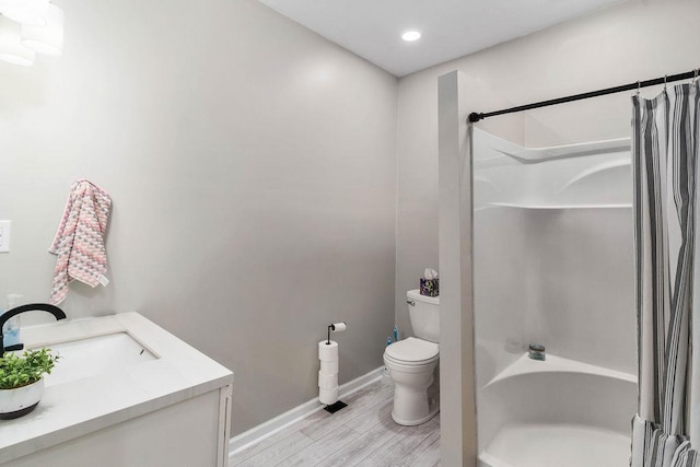 full bath featuring shower / bath combo, baseboards, toilet, wood finished floors, and vanity