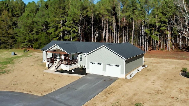 view of front of home with driveway, a garage, and a wooded view