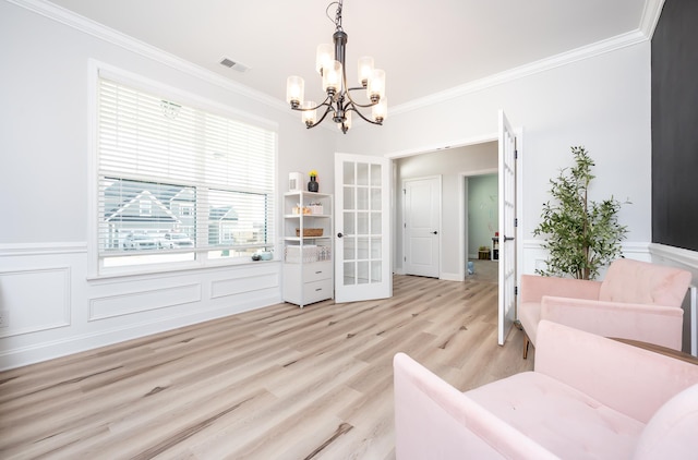 living area featuring light wood-type flooring, a wainscoted wall, visible vents, and crown molding