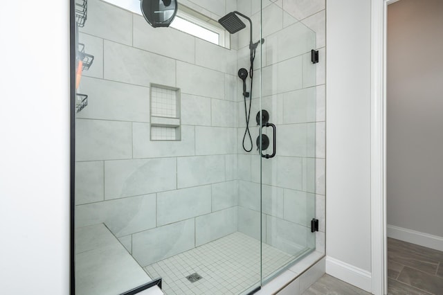 bathroom with a shower stall and baseboards