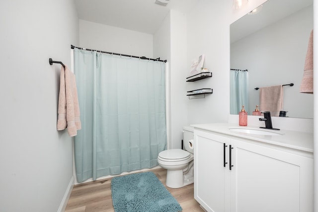 bathroom with toilet, curtained shower, wood finished floors, and vanity