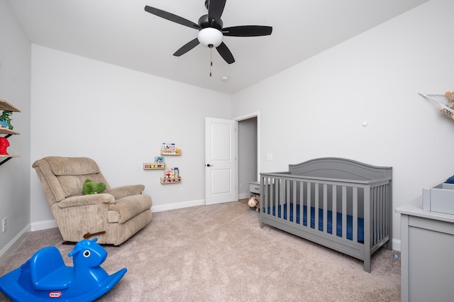 bedroom featuring a nursery area, carpet floors, a ceiling fan, and baseboards