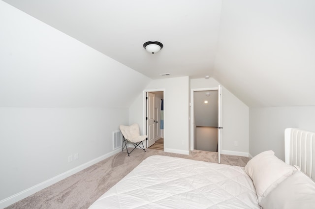 carpeted bedroom featuring lofted ceiling, visible vents, and baseboards