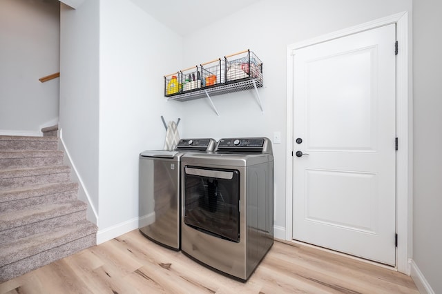 laundry room with laundry area, washer and clothes dryer, light wood-type flooring, and baseboards