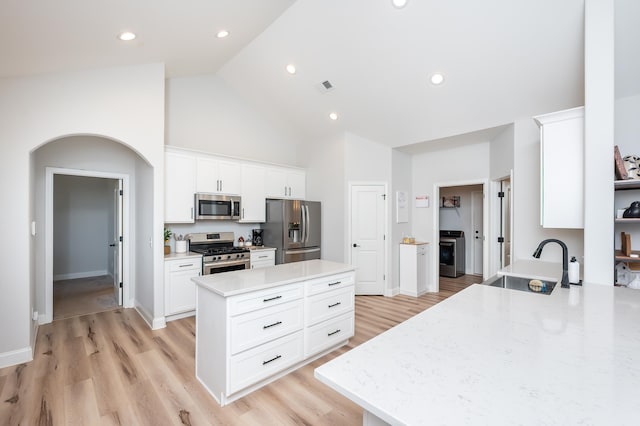 kitchen with a center island, arched walkways, stainless steel appliances, visible vents, and a sink