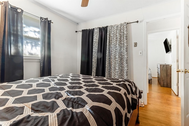 bedroom featuring ceiling fan, wood finished floors, and crown molding