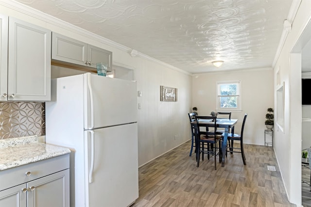 dining space featuring ornamental molding and light wood-style floors