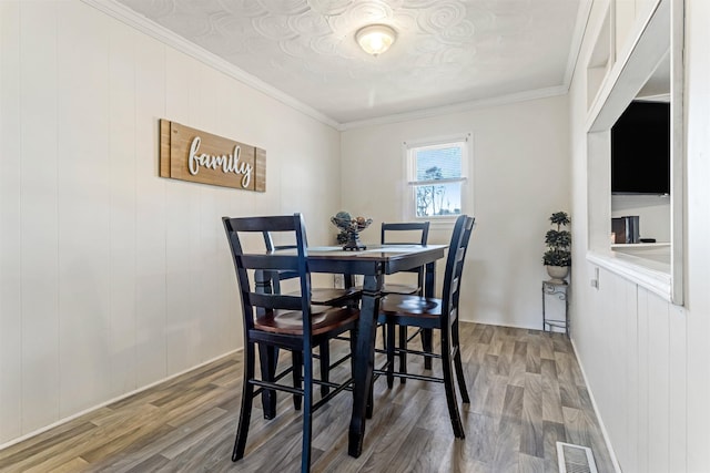 dining room with baseboards, crown molding, visible vents, and wood finished floors