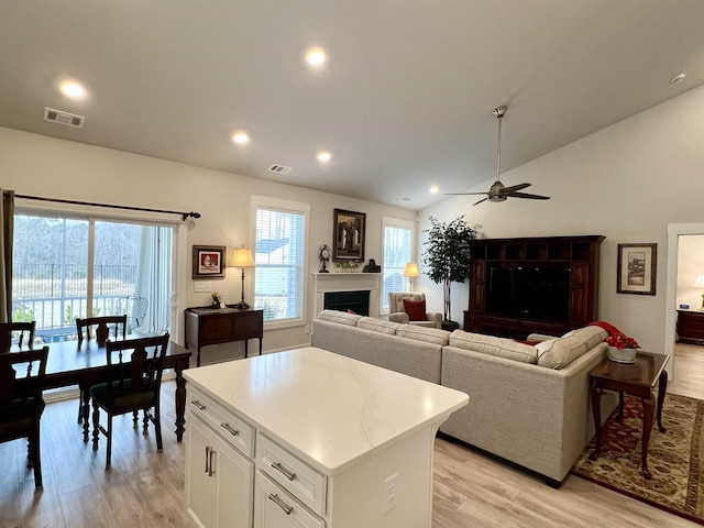 kitchen featuring lofted ceiling, light wood-style flooring, a fireplace, and visible vents