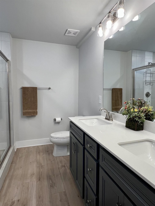 full bathroom featuring visible vents, toilet, a stall shower, a sink, and wood finished floors