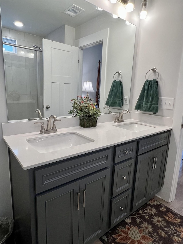 bathroom with double vanity, a shower stall, visible vents, and a sink