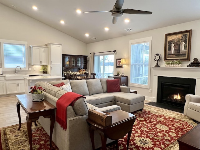 living room with visible vents, lofted ceiling, light wood-style flooring, a fireplace with flush hearth, and recessed lighting