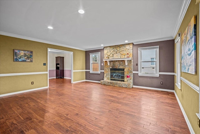 unfurnished living room with recessed lighting, a fireplace, wood finished floors, baseboards, and ornamental molding