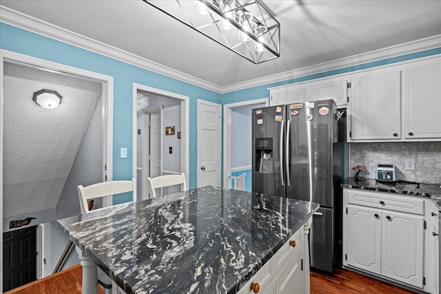 kitchen with dark wood-style floors, ornamental molding, white cabinets, a kitchen island, and stainless steel fridge