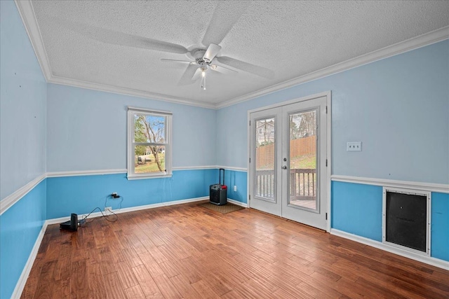 empty room with ornamental molding, french doors, wood finished floors, and a ceiling fan