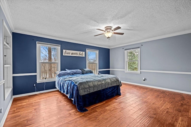 bedroom with ornamental molding, a textured ceiling, baseboards, and wood finished floors