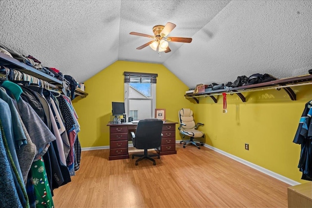 office featuring a textured ceiling, baseboards, lofted ceiling, and light wood-style floors