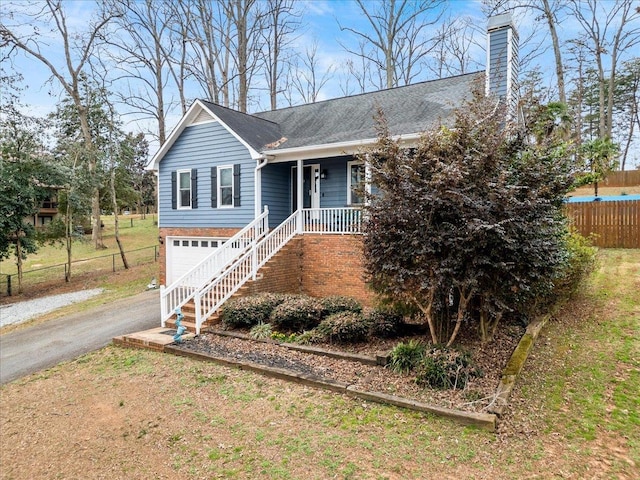 ranch-style house featuring aphalt driveway, a chimney, a porch, an attached garage, and fence