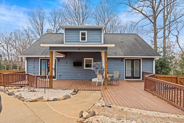 exterior space featuring french doors, roof with shingles, a chimney, fence, and a wooden deck