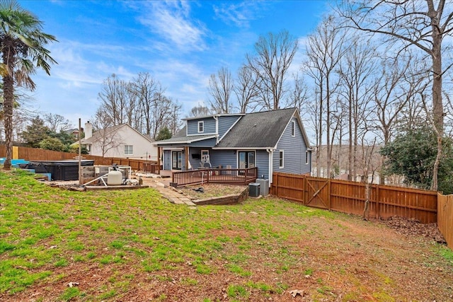 rear view of property featuring a hot tub, a fenced backyard, and a wooden deck