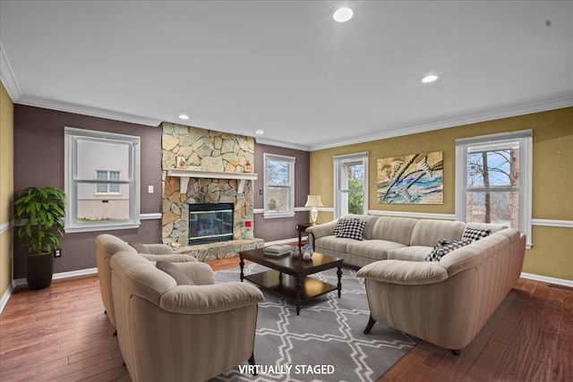 living room featuring wood-type flooring, ornamental molding, baseboards, and a stone fireplace