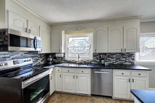 kitchen with dark countertops, appliances with stainless steel finishes, white cabinets, and a sink