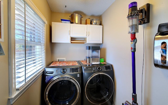laundry area featuring a textured ceiling, washing machine and dryer, and cabinet space